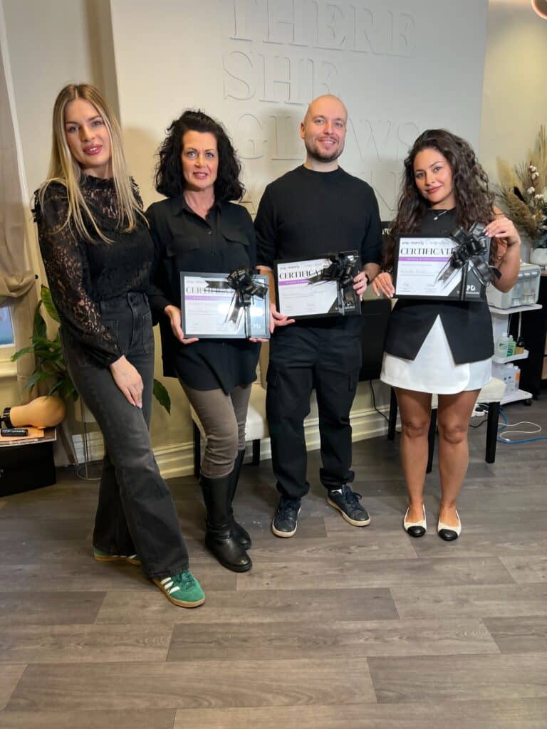 Ell with SMP-Clinic graduates holding their scalp micropigmentation certificates after completing training