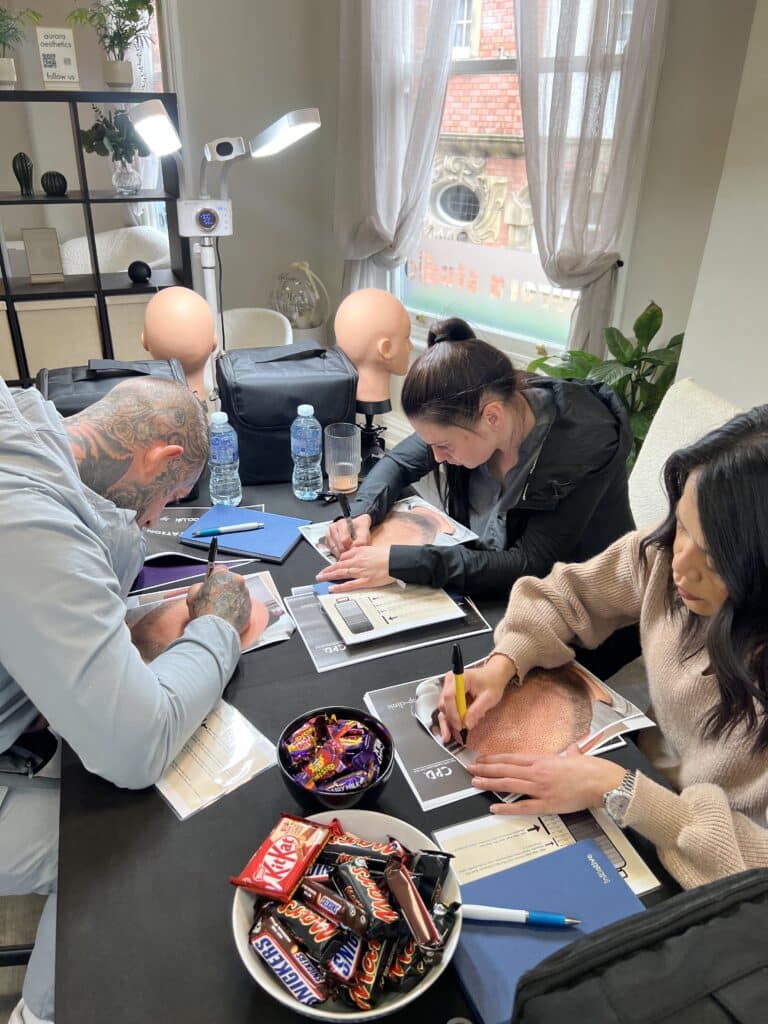 Students performing scalp micropigmentation on fake skins, training session at SMP-Clinic”